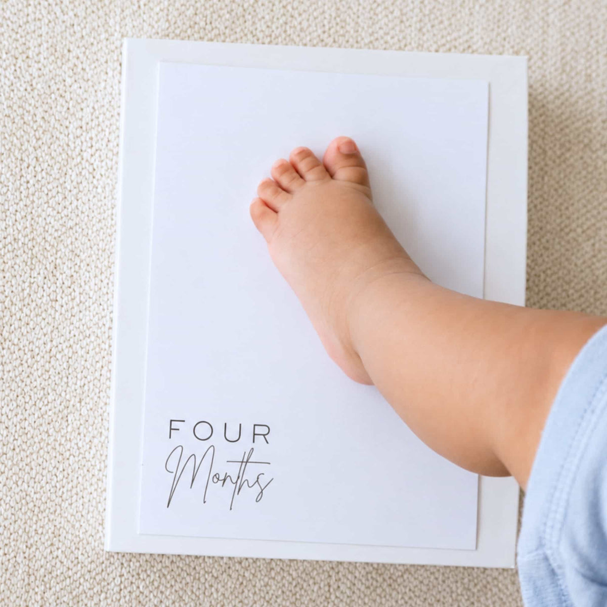 Pressing a baby's foot onto a Four Months inkless milestone card